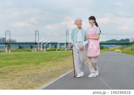 土手を散歩する日本人シニア女性と若い女性介護士 土手を散歩する日本人シニア女性と若い女性介護士 140290828