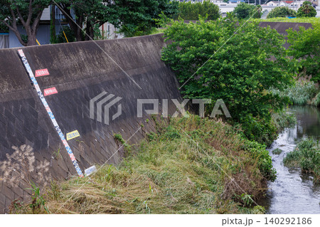 河川の護岸に設置された水位計(量水標)と氾濫危険水位の標識 河川の護岸に設置された水位計(量水標)と氾濫危険水位の標識 140292186