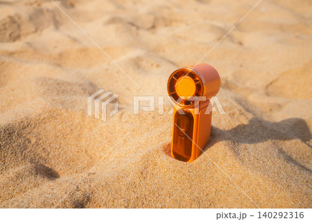 Portable handy fan on the beach and the background is the sea and the sky in summer. Portable handy fan on the beach and the background is the sea and the sky in summer. 140292316