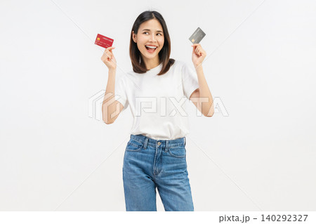 Happy young Asian woman holding credit cards with a confident smile isolated on white studio background. Happy young Asian woman holding credit cards with a confident smile isolated on white studio background. 140292327