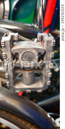 Close-up view of a folding bike pedal showcasing intricate design and durable materials, mounted on a bicycle frame with visible components in the background Close-up view of a folding bike pedal showcasing intricate design and durable materials, mounted on a bicycle frame with visible components in the background 140292829