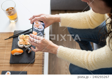 Person Eating Assorted Sushi with Chopsticks at Home Person Eating Assorted Sushi with Chopsticks at Home 140293267