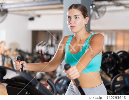 Young woman working out on elliptical machine Young woman working out on elliptical machine 140293648