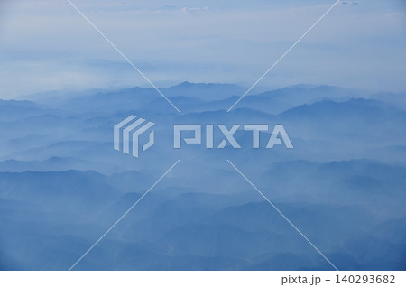 The view of the stunning landscape with mountains and clouds from the airplane window. Aerial view of the natural scene, mountain range. Travel and landscape scene. Travel and nature concept. The view of the stunning landscape with mountains and clouds from the airplane window. Aerial view of the natural scene, mountain range. Travel and landscape scene. Travel and nature concept. 140293682