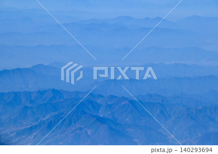 The view of the stunning landscape with mountains and clouds from the airplane window. Aerial view of the natural scene, mountain range. Travel and landscape scene. Travel and nature concept.  140293694