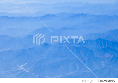 The view of the stunning landscape with mountains and clouds from the airplane window. Aerial view of the natural scene, mountain range. Travel and landscape scene. Travel and nature concept. The view of the stunning landscape with mountains and clouds from the airplane window. Aerial view of the natural scene, mountain range. Travel and landscape scene. Travel and nature concept. 140293695