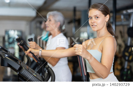 Portrait of sporty woman doing cardio workout on elliptical cross trainer at fitness center Portrait of sporty woman doing cardio workout on elliptical cross trainer at fitness center 140293729