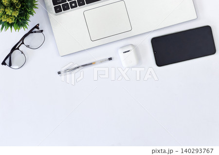 Minimalist workspace with sleek gadgets. Green phone rests beside laptop and mouse. White earbuds and pen add functional touch. Clean desk invites calm, focused productivity Minimalist workspace with sleek gadgets. Green phone rests beside laptop and mouse. White earbuds and pen add functional touch. Clean desk invites calm, focused productivity 140293767