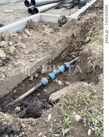 Plumbing, irrigation, or drainage project. a narrow trench dug into the ground for utility installation. Plumbing, irrigation, or drainage project. a narrow trench dug into the ground for utility installation. 140293894