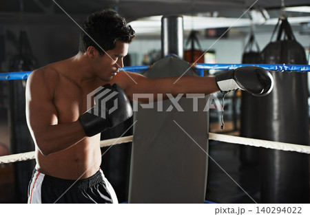 Punch, man and boxing ring for sports, exercise or competition in gym for body health. Fighter, serious and strong athlete with gloves for fitness, training or workout to practice with fist at club 140294022