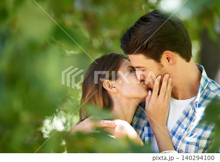 Couple, garden and kiss with love for date, bonding and romance with embrace in nature park. Man, woman and happy relationship with affection in summer for vacation, weekend or travel together 140294100
