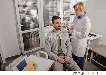 Adult man while tympanometry or impedance audiometry and test of middle-ear function with audiologist using tympanometer probe at hearing center 140294105
