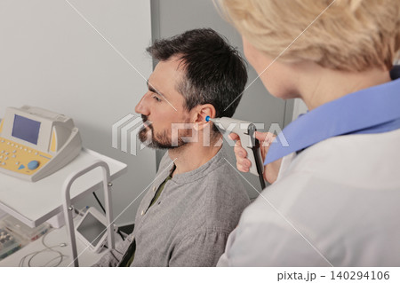 Adult man receives tympanometry with tympanometer probe at hearing clinic. Hearing check-up, impedance audiometry Adult man receives tympanometry with tympanometer probe at hearing clinic. Hearing check-up, impedance audiometry 140294106