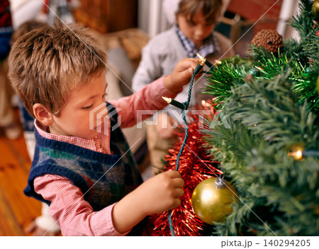 Little boy, decorating and tree for Christmas with ornaments, lights and celebration for season in season. Child, working and love for festive tradition in family home, kids and enjoying holiday Little boy, decorating and tree for Christmas with ornaments, lights and celebration for season in season. Child, working and love for festive tradition in family home, kids and enjoying holiday 140294205