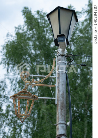 Metal street lamp pole supports a vintage lantern Metal street lamp pole supports a vintage lantern 140294287