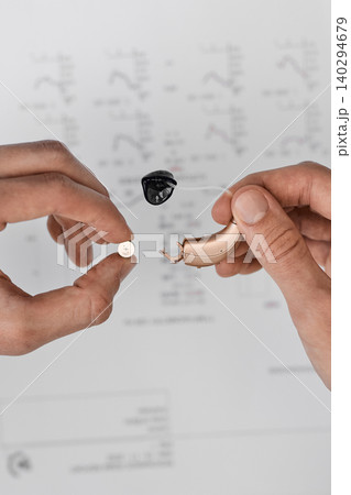 Audiologist showing a hearing clinic patient how to replace batteries for his hearing aid for maintenance. Hearing Solutions Audiologist showing a hearing clinic patient how to replace batteries for his hearing aid for maintenance. Hearing Solutions 140294679