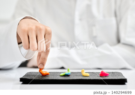 Doctor audiologist demonstrates different types of individual colorful earplugs that are presented on hearing clinic table for patient to choose from. Hearing solutions Doctor audiologist demonstrates different types of individual colorful earplugs that are presented on hearing clinic table for patient to choose from. Hearing solutions 140294699