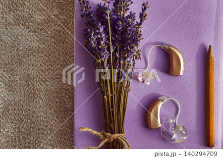 Lavender blooms complementing advanced hearing aids and a pencil, representing innovative sound treatment methods and hearing treatment Lavender blooms complementing advanced hearing aids and a pencil, representing innovative sound treatment methods and hearing treatment 140294709