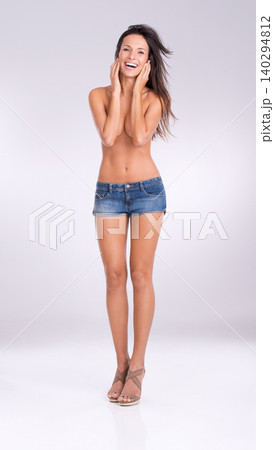 Portrait, smile and shorts with naked woman in studio on gray background for feminine confidence. Fashion, sexy and shirtless with body of happy young model in denim for style or natural sensuality Portrait, smile and shorts with naked woman in studio on gray background for feminine confidence. Fashion, sexy and shirtless with body of happy young model in denim for style or natural sensuality 140294812