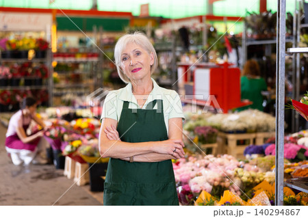 Portrait of benevolent owner of flower market against the background of bouquets and potted flowers Portrait of benevolent owner of flower market against the background of bouquets and potted flowers 140294867