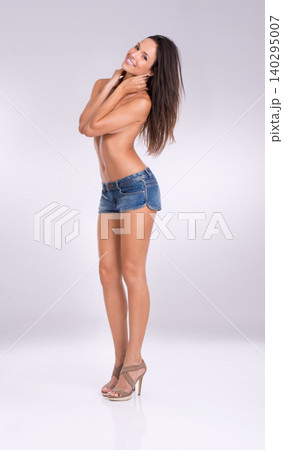 Portrait, smile and denim shorts with woman in studio on gray background for feminine confidence. Fashion, sexy and shirtless with body of happy young model in jeans for style or natural sensuality Portrait, smile and denim shorts with woman in studio on gray background for feminine confidence. Fashion, sexy and shirtless with body of happy young model in jeans for style or natural sensuality 140295007