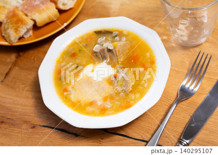 Traditional Russian soup rassolnik made from pickled cucumbers, pearl barley and beef kidneys decorated by sour cream 140295107