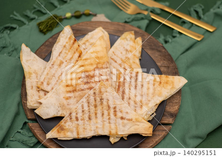 Pita bread with cheese baked on grill. Thin, crispy triangular flatbreads with filling. Food on plate Pita bread with cheese baked on grill. Thin, crispy triangular flatbreads with filling. Food on plate 140295151