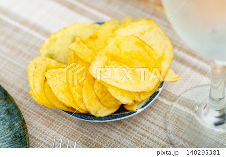 Plate of crispy deep-fried chips of thinly sliced potatoes 140295381