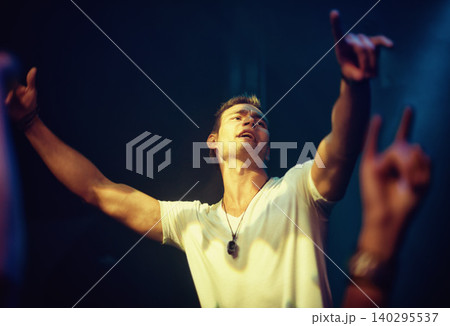 Dance, music and night with man at concert for performance, energy and rock festival. Party, nightclub and event with excited male person and arms raised for musician, disco and rave culture Dance, music and night with man at concert for performance, energy and rock festival. Party, nightclub and event with excited male person and arms raised for musician, disco and rave culture 140295537