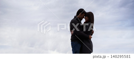 Couple, sky and hug together with love for romance, commitment and care for feeling safe. Man, woman and relationship with mockup, space and banner outdoors on honeymoon with spouse comfort and trust Couple, sky and hug together with love for romance, commitment and care for feeling safe. Man, woman and relationship with mockup, space and banner outdoors on honeymoon with spouse comfort and trust 140295581
