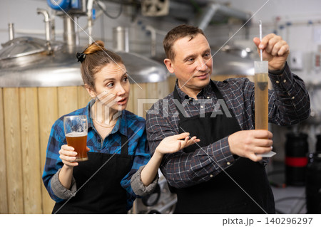 Woman and a man check the amount of alcohol in beer at private brewery Woman and a man check the amount of alcohol in beer at private brewery 140296297