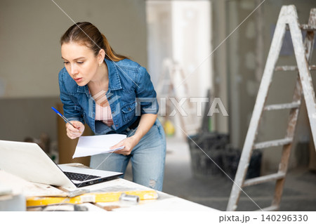 Woman with laptop at house being renovated Woman with laptop at house being renovated 140296330