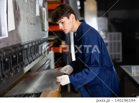Young worker works on sheet bending machine at metallurgical plant Young worker works on sheet bending machine at metallurgical plant 140296594