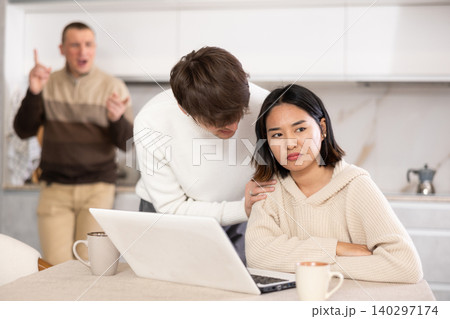 Guy persuades a young girl to stop playing computer games. Upset father in background Guy persuades a young girl to stop playing computer games. Upset father in background 140297174