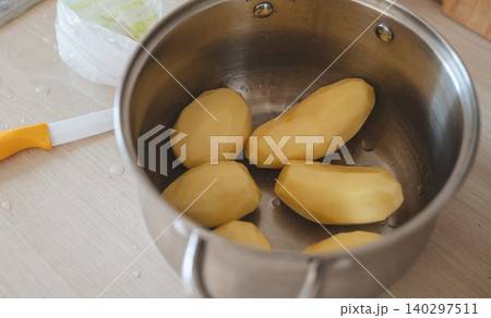 Peeled raw potatoes in a saucepan with water 140297511