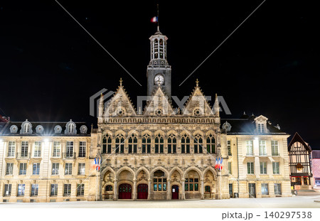 The illuminated facade of the historic Mairie de Saint Quentin features flamboyant gothic architecture and a tall clock tower at night in northern France. The illuminated facade of the historic Mairie de Saint Quentin features flamboyant gothic architecture and a tall clock tower at night in northern France. 140297538