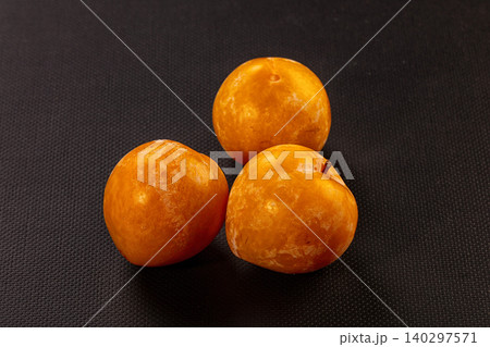 Three fresh golden plums on dark background. Ripe sweet fruits ready for eating Three fresh golden plums on dark background. Ripe sweet fruits ready for eating 140297571