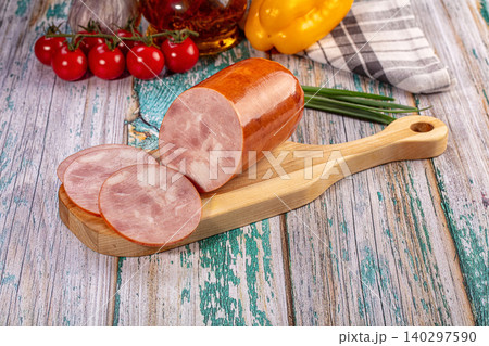 Cooked ham sausage and slices on rustic table with tomatoes and pepper 140297590