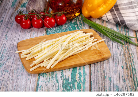 Smoked string cheese on bamboo board with fresh tomatoes, pepper, and garlic on rustic wooden table Smoked string cheese on bamboo board with fresh tomatoes, pepper, and garlic on rustic wooden table 140297592