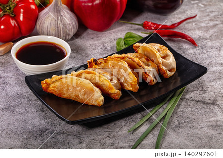 Fried gyoza dumplings on black plate with soy sauce and vegetables 140297601