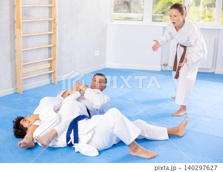 Male athletes in pair conduct training battle in oriental fighting technique under guidance of coach Male athletes in pair conduct training battle in oriental fighting technique under guidance of coach 140297627