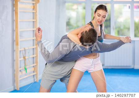 Young woman learning to do power grab on an opponent neck during self-defense training at gym Young woman learning to do power grab on an opponent neck during self-defense training at gym 140297707