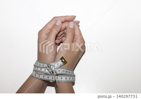 Measuring tape restraining hands as symbol of eating disorder Measuring tape restraining hands as symbol of eating disorder 140297731