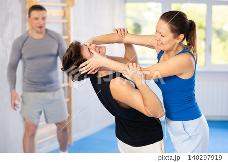 Self-defense class - woman makes painful hold in eyes of an attacking man under the guidance of trainer Self-defense class - woman makes painful hold in eyes of an attacking man under the guidance of trainer 140297919
