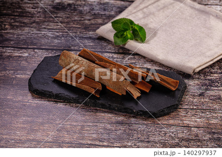 Aromatic cinnamon sticks with fresh mint on black slate board over dark wood background Aromatic cinnamon sticks with fresh mint on black slate board over dark wood background 140297937