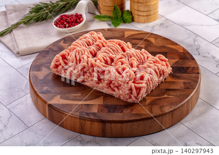 Raw ground chicken on round wooden cutting board with fresh herbs and spices Raw ground chicken on round wooden cutting board with fresh herbs and spices 140297943