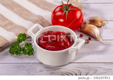 Tomato ketchup in white bowl with fresh ingredients like tomato, garlic, and parsley on wooden table 140297951