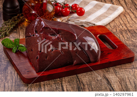 Raw beef liver on wooden cutting board with fresh herbs and tomatoes Raw beef liver on wooden cutting board with fresh herbs and tomatoes 140297961