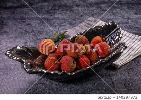 Fresh ripe red lychee fruits in decorative black bowl on dark textured background Fresh ripe red lychee fruits in decorative black bowl on dark textured background 140297972