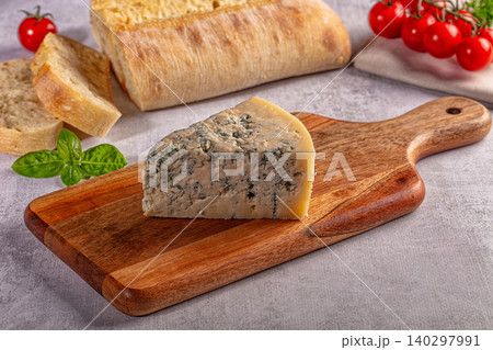 Blue cheese wedge on wooden board with bread and tomatoes 140297991